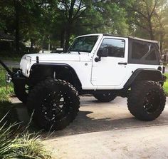 a white jeep parked on the side of a road next to some grass and trees