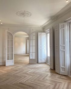 an empty room with white doors and wooden floors