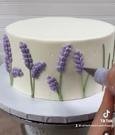 someone is decorating a cake with lavender flowers