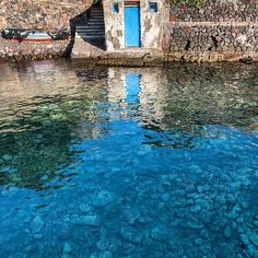 the water is crystal clear and blue in this small village with stone buildings on it's sides