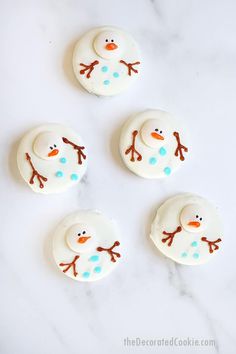 four frosted snowman cookies sitting on top of a white counter