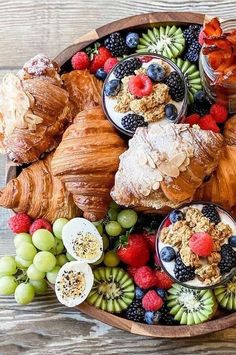 an assortment of fruits and pastries on a platter with croissants