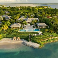 an aerial view of a house and pool surrounded by lush greenery, with the ocean in the background