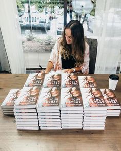 a woman sitting at a table in front of a stack of books with the title your day written on it