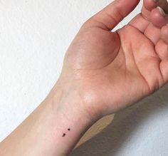 a person's hand with a tiny black dot on the middle of their wrist