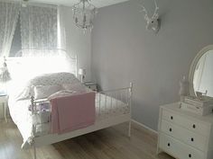 a white bed sitting in a bedroom next to a dresser and mirror on top of a hard wood floor