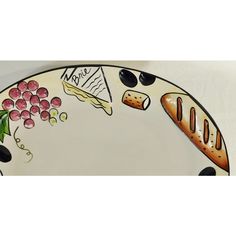 a plate that has some food on it and is decorated with grapes, bread, cheese, and wine