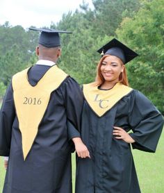 two people in graduation gowns posing for the camera