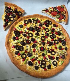 a pizza with olives, peppers and other toppings on it next to two slices of pizza