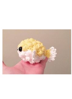 a hand holding a small crocheted toy fish in it's right hand