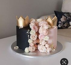 a pink and black cake with flowers on it sitting on top of a white table