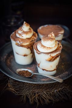 three desserts are sitting on a plate with a spoon in front of them and one is topped with whipped cream