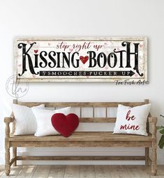 a wooden bench with two pillows and a sign on the wall above it that says, stop right up kissing booth