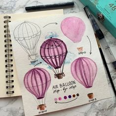 a drawing of hot air balloons on top of a notebook