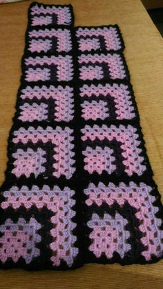 two crocheted black and pink squares sitting on top of a table