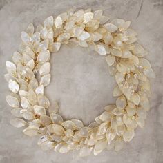 a wreath made out of shells sitting on top of a cement floor next to a wall