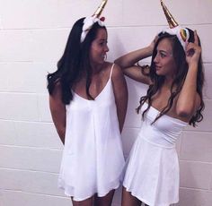 two women in white dresses standing next to each other with gold hair clips on their head