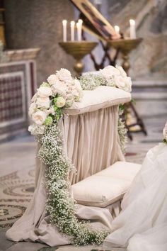 a chair covered in flowers and greenery next to a candle lit aisle with candles on either side