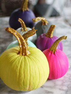 three small pumpkins with gold sequins in them on a marble counter top