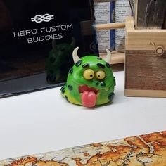 a green monster figurine sitting on top of a table next to a book