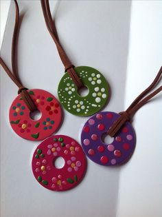 three different colored donuts are hanging on a brown leather cord with holes in the middle