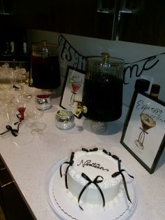 a white cake sitting on top of a counter next to wine glasses and framed pictures