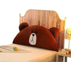 a brown teddy bear pillow sitting on top of a bed next to a night stand