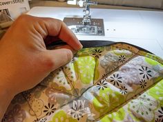 a person is sewing on a machine with a green and white flowered bag in front of them