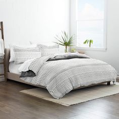 a bed with white sheets and pillows in a room next to a wooden ladder, potted plant and window