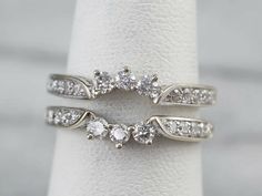 two white gold wedding rings with diamonds on each side and one diamond set in the middle