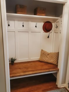 a wooden bench with baskets on top of it in front of a white wall and door