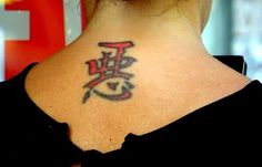 a woman with a tattoo on her upper back neck and the word love written in chinese