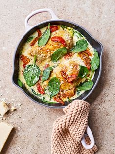 a pan filled with spinach and cheese next to a mitt