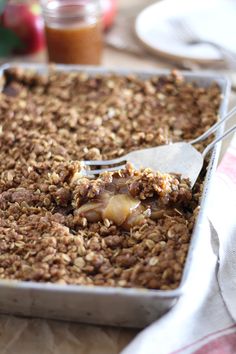 a close up of a pan of food with a fork in it and some fruit on the side