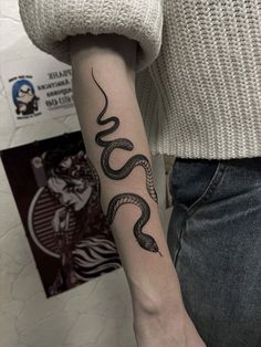 a woman's arm with a snake tattoo on the left side of her arm