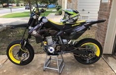 a yellow and black motorcycle parked in front of a house