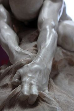 a close up of a statue with hands on it's knees and one hand resting on the ground