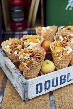 several cones filled with fruit sitting on top of a wooden crate