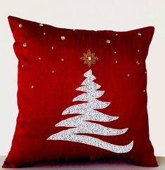 a red pillow with a white christmas tree on it