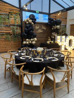 a table set up with black and gold balloons