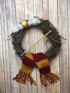 a knitted harry potter inspired wreath with a wand and two white feathers on it