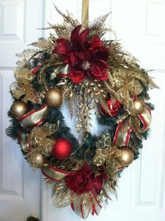 a christmas wreath hanging on the front door with red and gold ornaments around it's edges