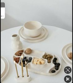 a white table topped with plates and bowls filled with different types of food next to candles