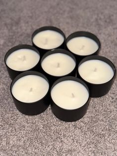 six white candles are arranged in the shape of a heart on a carpeted floor