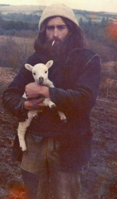 a man holding a baby goat in his arms