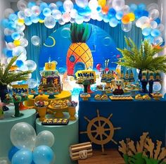 a party with balloons, pineapples and other items on the table in front of an ocean themed backdrop