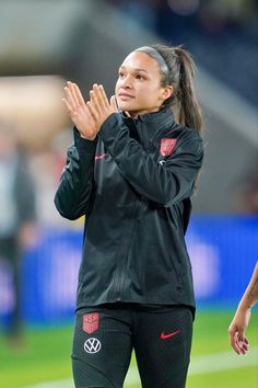 a female soccer player is applauding her team's play on the field