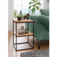 a living room with a green couch and a table in front of a window that has a plant on it