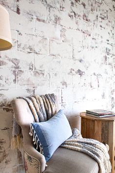 a living room with a couch, table and lamp on the side walk in front of a white brick wall