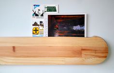 a wooden shelf with books and magazines on it next to a wall mounted photo frame